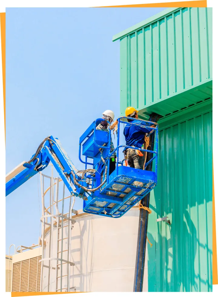 Two workers in a blue boom lift basket beside a building