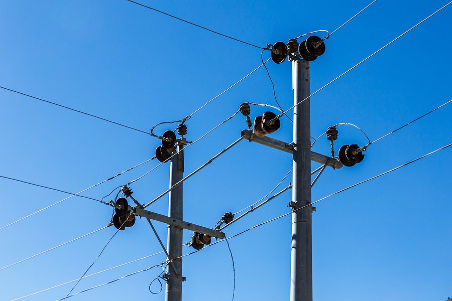 Electrical power lines and utility poles against a blue sky