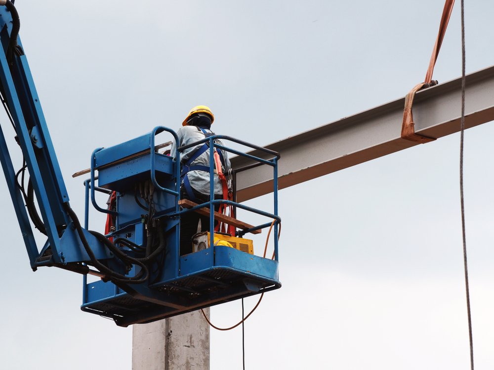 Worker on a boom lift platform beside a steel beam